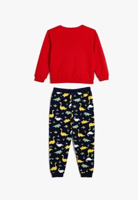 Camiseta roja de manga larga con cuello redondo combinada con pantalones de pijama azul marino que presentan coloridos patrones de dinosaurios en amarillo, verde y blanco. Tela de algodón.