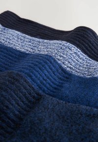 Gestrickte Decke in verschiedenen Blautönen, mit strukturierten Streifen aus dunklem Marineblau und hellerem Blau, die eine wellenartige Erscheinung erzeugen.