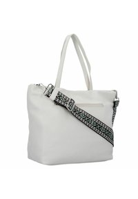 Witte getextureerde tote bag met twee lange handvatten en een patroonriem met geometrische ontwerpen in zwart en mintgroen. Ritszakdetail.