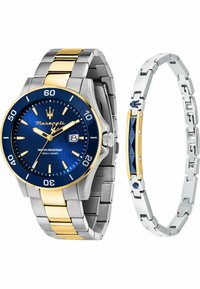 Silberne und goldfarbene Metall-Uhr mit blauem strukturiertem Zifferblatt, Datumfenster und goldenen Akzenten; begleitet von einem silbernen Armband mit blauen Details.