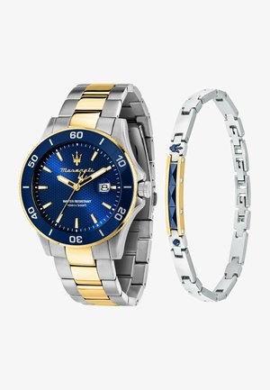 Silberne und goldfarbene Metall-Uhr mit blauem strukturiertem Zifferblatt, Datumfenster und goldenen Akzenten; begleitet von einem silbernen Armband mit blauen Details.