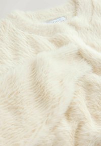 Cremefarvet, fluffy sweater med en blød tekstur. Har en rund halsudskæring og en afslappet pasform. Stoffet har en let glans.