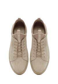 Sneakers in suede beige con punta tondeggiante, suola piatta in gomma, sistema di allacciatura centrale e linguetta sul tallone. Texture liscia con design minimalista.