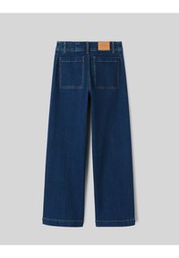 Jean large en denim bleu foncé avec un empiècement arrière, deux poches arrière et une étiquette en cuir marron clair à la ceinture.