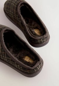 Braun karierte Hausschuhe mit flauschiger Innenseite und Gummisohle. Weicher Stoffobermaterial mit gesticktem Rand und Logo auf der Innensohle.