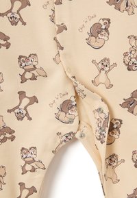 Hellbeige Einteiler mit einem wiederholten Muster von animierten Eichhörnchen, Chip und Chap, mit Druckknöpfen am unteren Ende zur Befestigung.
