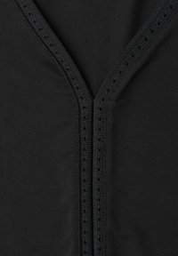 Gros plan sur un tissu noir avec un décolleté en V orné d'une bordure texturée présentant de petits œillets.