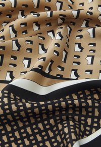 Satin scarf featuring a brown base with black and white geometric patterns, accented by solid black and white borders. Soft, smooth texture.