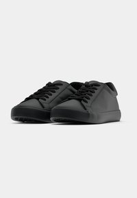 Mustad mustad mustad, ümar varvas, lapik kummist tall, ja mustad nöörid. Minimalistlik disain ilma nähtavate logode või mustriteta.