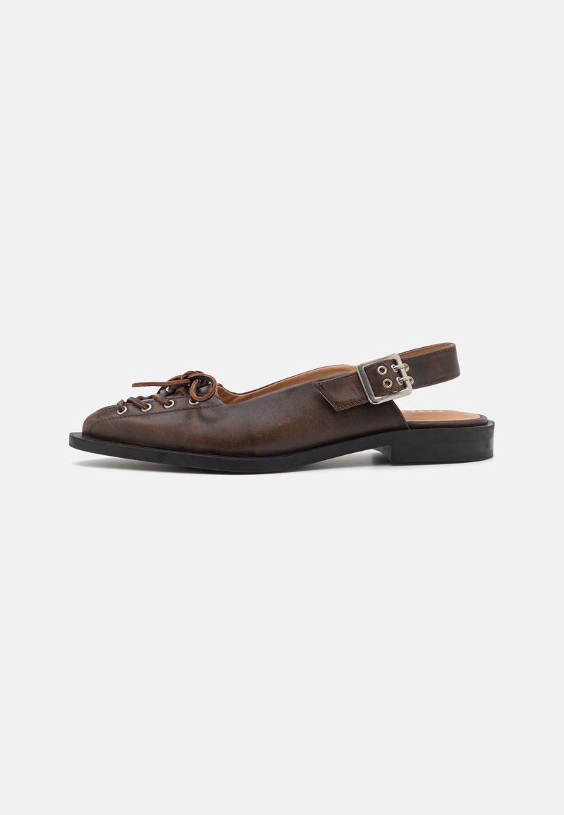 Brūna ādas slingback kurpe ar platu papēdi, noapaļotu purngali un auklu priekšpusi, kā arī sudraba sprādzi uz siksniņas.