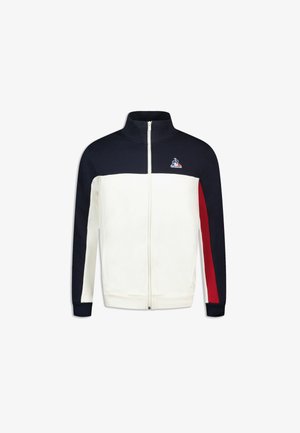 Chaqueta con cremallera con un cuerpo blanco, mangas marinas y acentos rojos. Presenta un cuello alto y un logo en el pecho. Fabricada con un tejido suave.