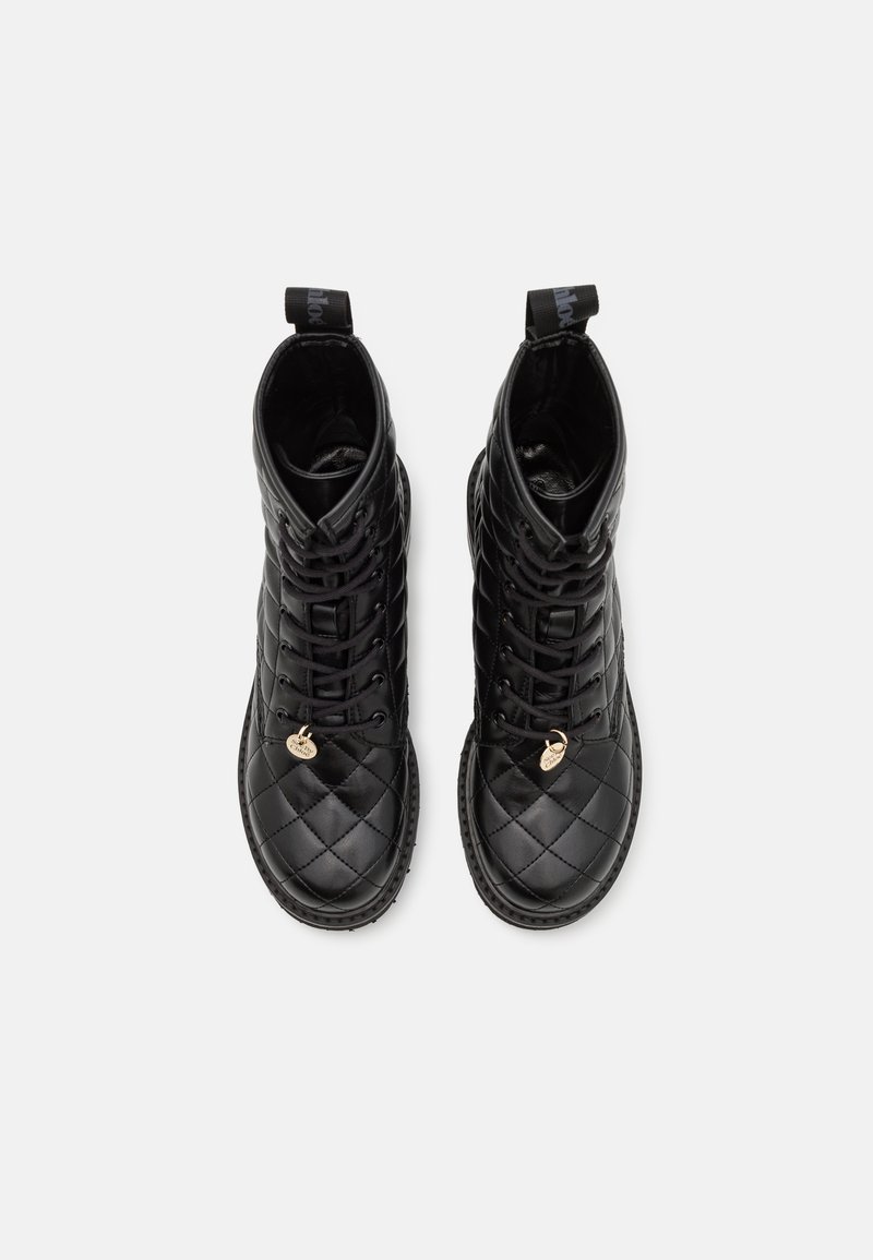 Stivaletti alla caviglia in pelle nera trapuntata con lacci tondi, finitura testurizzata, accenti con logo e linguette sul tallone.
