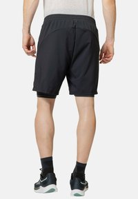 Schwarze Sportshorts mit einem elastischen Bund, die eine glatte Textur und eine enge Passform haben. Die Shorts reichen bis zur Mitte des Oberschenkels.