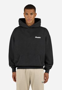 Black, oversized hoodie made of cotton with a front pocket. Features a small white logo on the chest and ribbed cuffs and hem.