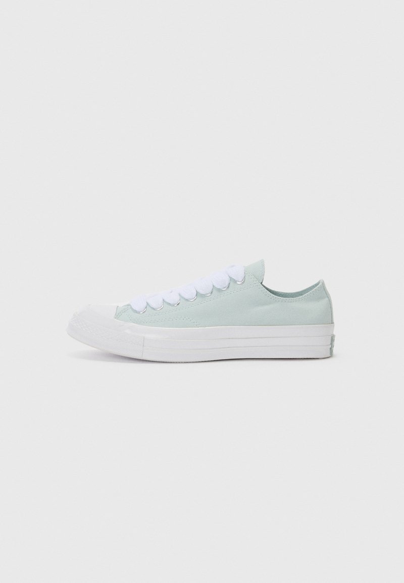 Light mint green canvas sneaker with white laces and rubber sole. Rounded toe and low-profile design. Smooth texture with minimal detailing.