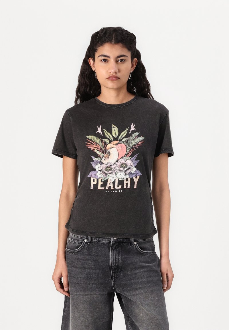 Musta lyhythihainen t-paita, jossa on värikäs persikka- ja kukkagraafika sekä teksti "PEACHY AS CAN BE" kuluneella fontilla.