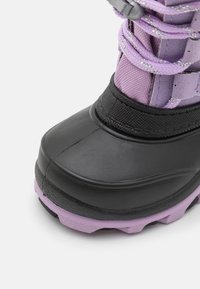 Černá zimní boty s texturovaným povrchem, s fialovým svrškem a šedými šňůrkami; zaoblená špička a vyztužená gumová podrážka pro lepší přilnavost.