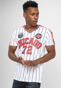 Hvid baseballtrøje med sorte striber, rød "CHICAGO 72" skrift og logo-patches på brystet. V-hals og korte ærmer.