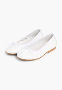 Ballerines blanches à bout rond, fabriquées en matériau lisse, avec un accent en nœud et une semelle brun clair.