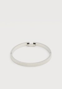 Βραχιόλι από ασημένιο μέταλλο με υφή από αυλακώσεις και μικρό, ορθογώνιο κούμπωμα, τοποθετημένο σε απλό λευκό φόντο.