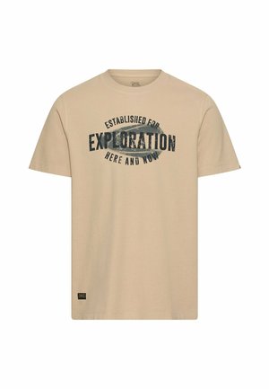 T-shirt beige à manches courtes avec texte noir "Established for Exploration Here and Now" et une petite étiquette noire près de l'ourlet.