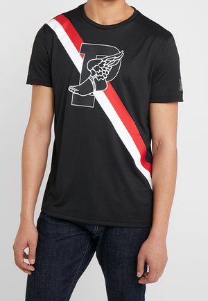 T-shirt noir à manches courtes avec des rayures diagonales rouges et blanches et un graphisme de pied ailé sur une grande lettre P sur la poitrine.