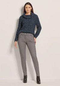 Marineblauwe gebreide trui met een col, gecombineerd met grijze slim-fit broek en zwarte enkellaarsjes. De trui heeft een gestructureerd patroon door het hele stuk.