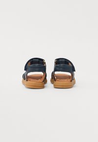 Marine sandaler med åpen bakdesign, med justerbare stropper og en polstret brun innersåle, plassert på en lett gummisåle.