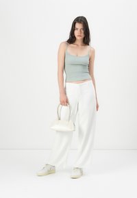 Ανοιχτό πράσινο ριγέ τοπ, λευκό παντελόνι με φαρδιές γραμμές και κρεμ τσάντα με κοντές λαβές. Τα αθλητικά παπούτσια είναι ανοιχτό γκρι με κρεμ σόλες.