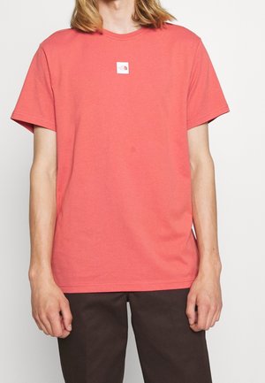 Kurzärmeliges Korallen-T-Shirt aus Baumwolle. Verfügt über ein kleines weißes Logo-Patch auf der Brust. Einfaches Rundhals-Design mit lockerer Passform.