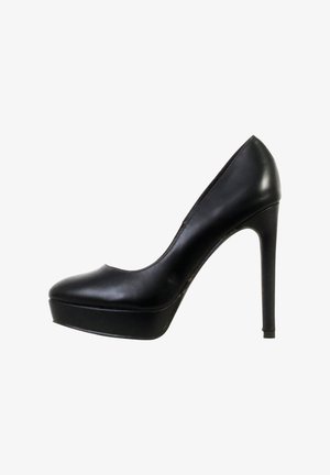 Escarpin à plateforme à talon haut en cuir noir, bout pointu et talon stiletto fin, vu de profil sur fond blanc.