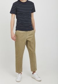 Námořnické pruhované tričko s krátkým rukávem, spárované s světle hnědými manšestrovými kalhotami tapered a bílými teniskami. Jednoduchý design, pohodlný střih.