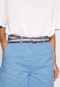 Bawełniany pas w szaro-białe paski, z czerwonymi i niebieskimi akcentami, zapinany na srebrną klamrę w kształcie D.