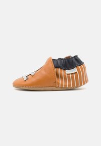 Sahnefarbene Lederschuhe mit elastischem Knöchel, ausgestattet mit navyfarbenem Stoff und weißen vertikalen Streifen. Dekorative beige Akzente vorne. Flacher Absatz.