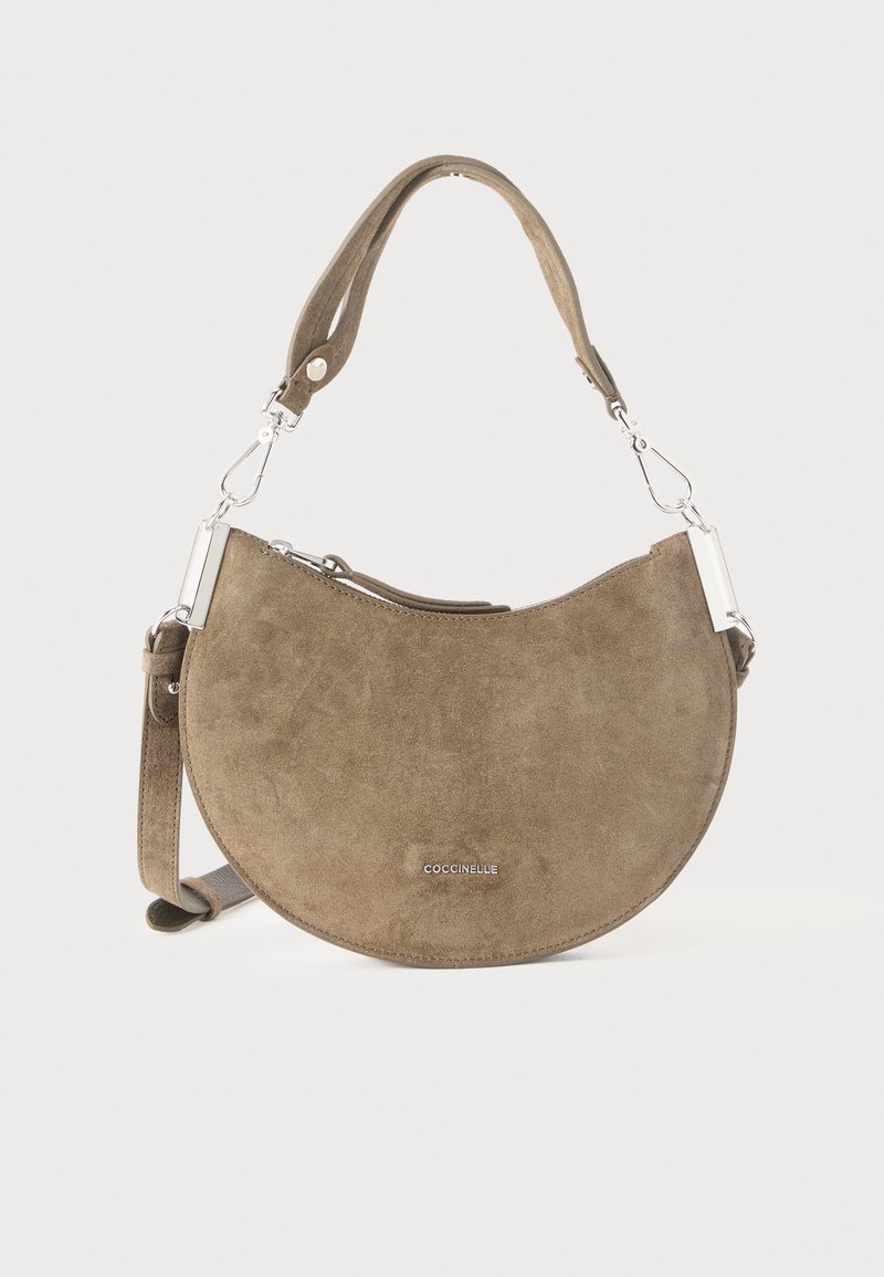 Sac à main en daim marron en forme de croissant avec bandoulière détachable et ferrures argentées, marqué "Coccinelle" sur le devant.