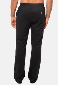 Zwarte katoenen joggingbroeken met een verstelbare tailleband, voorzien van een ritszak aan de achterkant en een relaxte pasvorm, ontworpen voor comfort en bewegingsgemak.