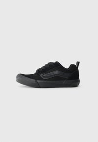 Sneakers en suede noir et caoutchouc avec bout arrondi, lacets à l'avant et couture ton sur ton. Dispose d'une semelle en caoutchouc texturée et d'une languette au talon.
