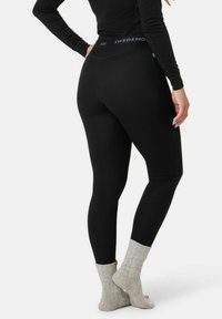 Schwarze Rippleggings mit breitem Bund und blauer "SWEDEMORE"-Markierung, kombiniert mit hellgrauen Rippstrümpfen.