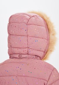 Rosa vadderad jacka med flerfärgade glittrande prickar, med en beige faux fur-kant på huvan och knapprar detaljer vid kragen.