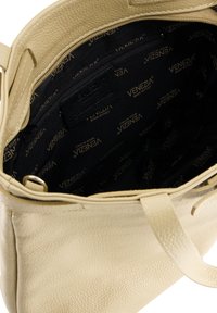 Beige læder tote taske med tekstureret yderside, med sort inderside foret med det gentagne "VENEZIA"-logo og en lynlåslomme.