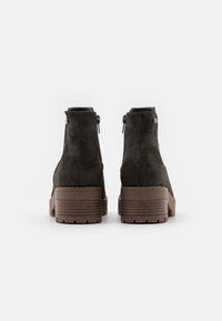 Ciemnoszare zamszowe botki za kostkę z drewnianymi, piętrowymi obcasami i tylnymi zamkami błyskawicznymi, widoczne od tyłu na białym tle.