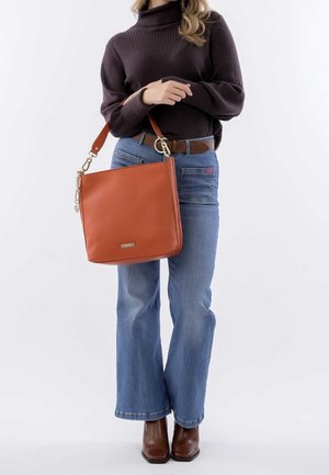 Maglione a collo alto a coste marrone, jeans a vita alta con gamba svasata e borsa a tracolla in pelle arancione con accessori in metallo dorato.
