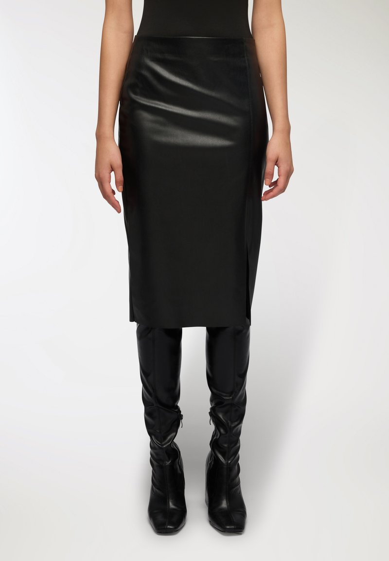 Gonna midi in pelle nera con una texture liscia e elegante e spacchi laterali, abbinata a stivali neri attillati fino al ginocchio.