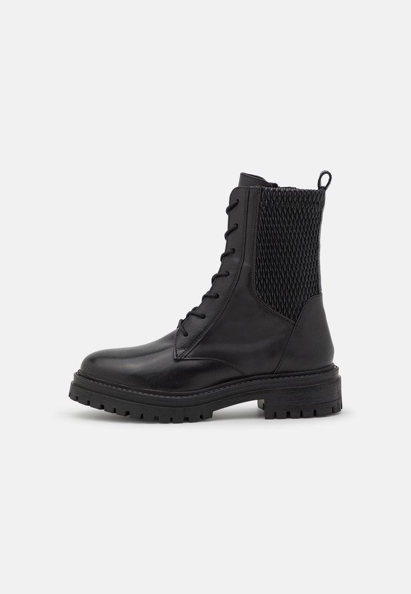 Schwarze Lederkampfstiefel mit dicker Sohle, Schnürung vorne und strukturiertem gepolstertem Rückenteil, auf einem weißen Hintergrund dargestellt.