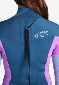 Wetsuit featuring blue and pink panels, smooth texture, zipper closure, and logo detail on the back with a black strap for adjustment.