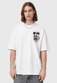 Hvit bomulls-t-skjorte med et grafisk design av en skalle, palmer og en sol. Ledig passform med korte ermer og rund hals.