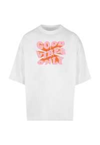 Balta didelė t-shirt marškiniai su užrašu "GEROS VIBRACIJOS TIK" gradientinėmis rožinėmis ir oranžinėmis raidėmis. Trumpomis rankovėmis, apvaliu iškirpimu, pagaminta iš minkštos medvilnės.
