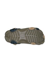 Tacón de un zapato con una suela de goma texturada en verde oliva y marrón. Patrón de agarre notable con acentos negros en los costados. Diseño duradero.