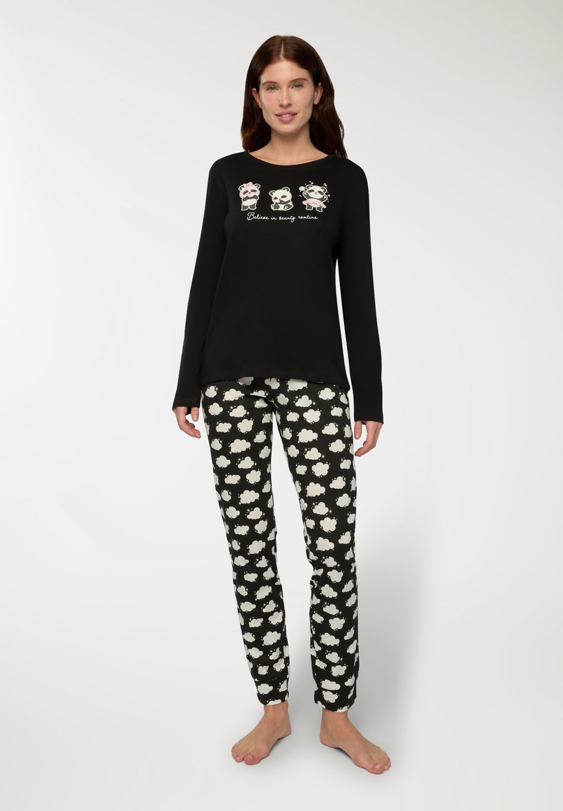 Maglietta da pigiama a maniche lunghe nera con grafiche di panda e testo; pantaloni neri a fantasia con forme di nuvole bianche. Tessuto di cotone morbido, vestibilità comoda.