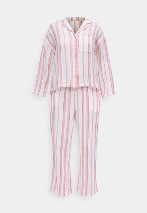 Balti medvilniniai pižamų rinkinys su raudonomis vertikaliomis juostelėmis. Ilgomis rankovėmis mygtukais užsegamas viršus su šonine kišene; atitinkantys laisvi kelnių su apdorotais kraštais.